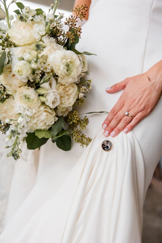 Bride showing engagement ring, dress, and holding flower bouquet