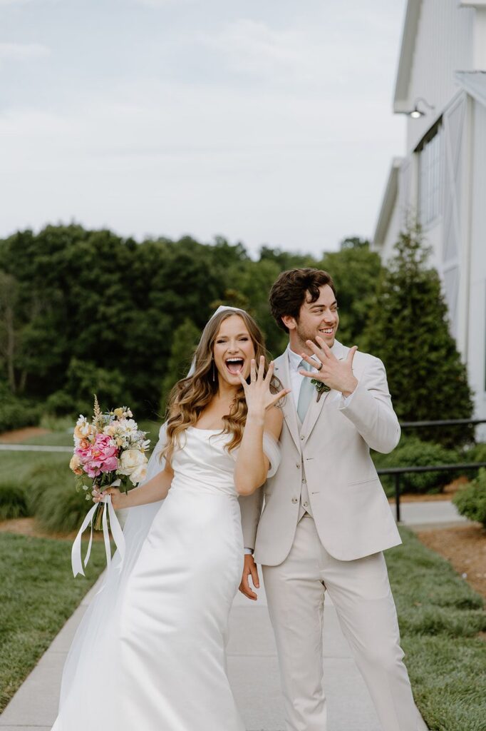 Bride and groom holding up hands showing wedding rings