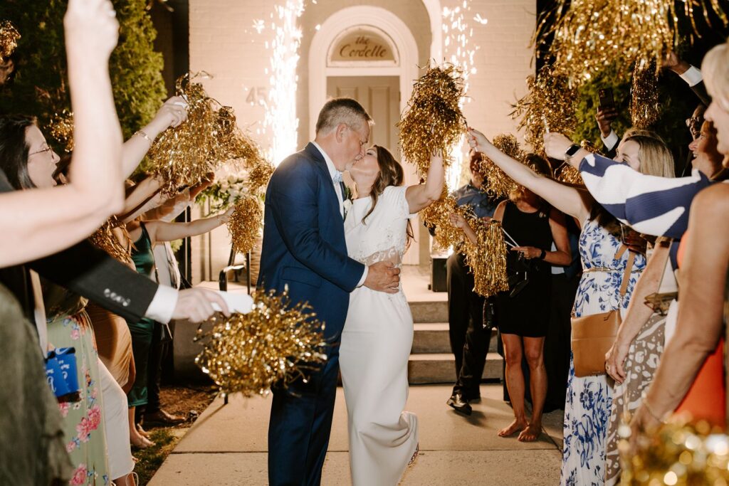 Wedding grand exit with pom poms bride and groom kissing 