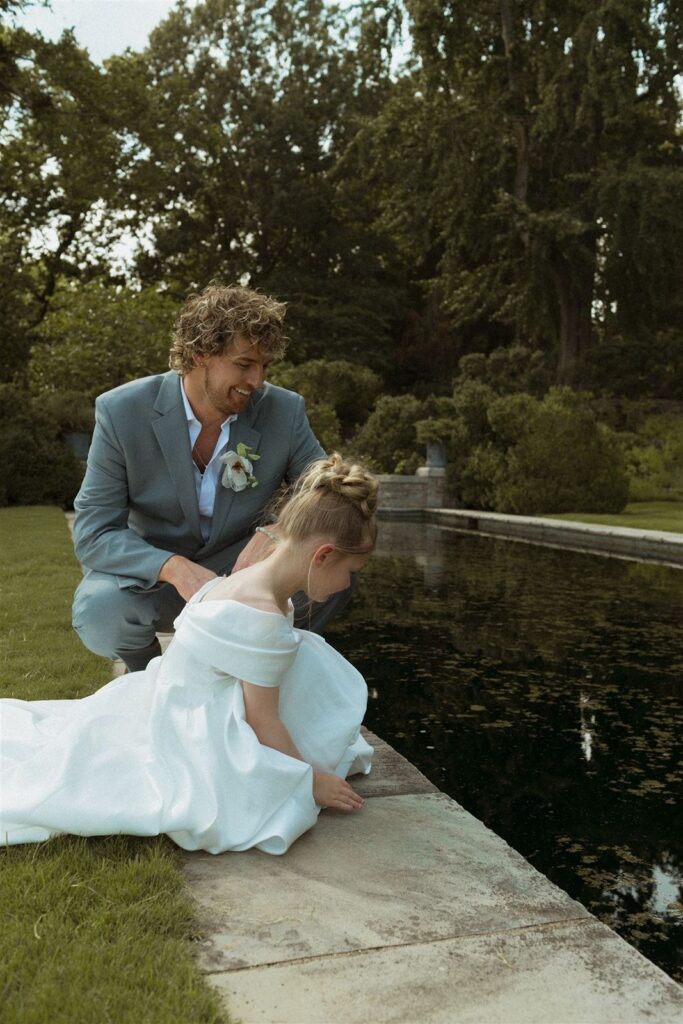 Groom and flower girl looking at pond