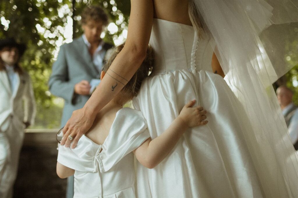 Bride and flower girl hugging 