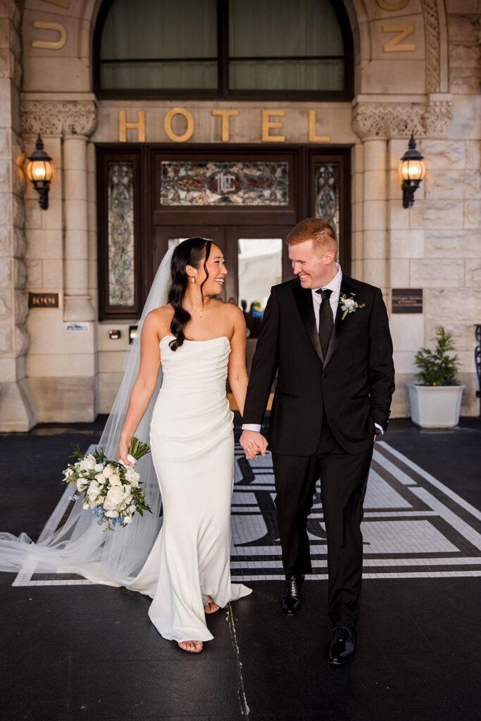 Bride and groom holding hands walking outside Union Station Hotel in Nashville, TN