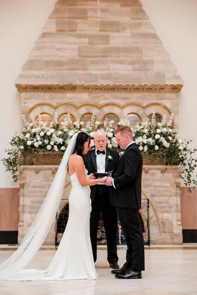 Bride and groom hold hands during wedding ceremony with officiant