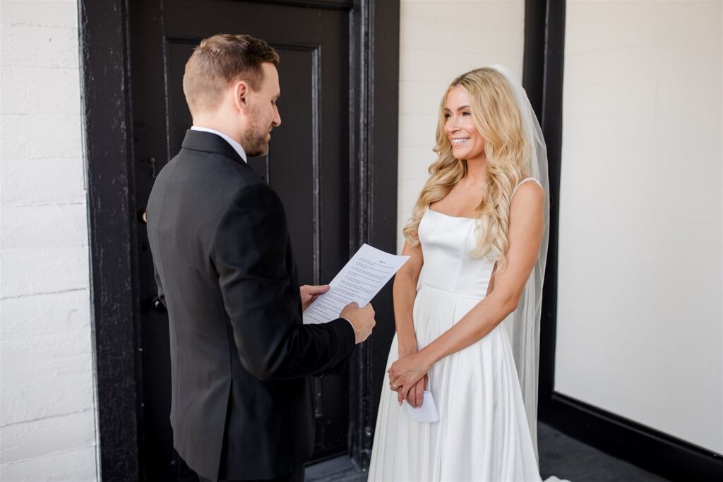 Groom reading personalized wedding vows to bride