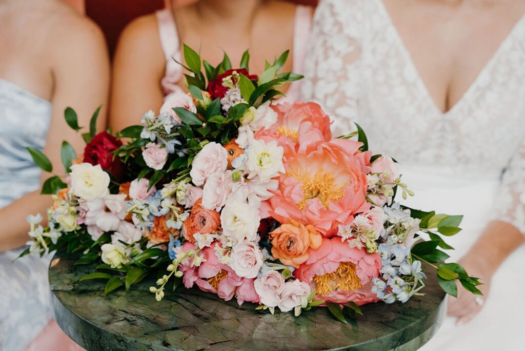 Bride and bridesmaids sitting behind floral arrangements.