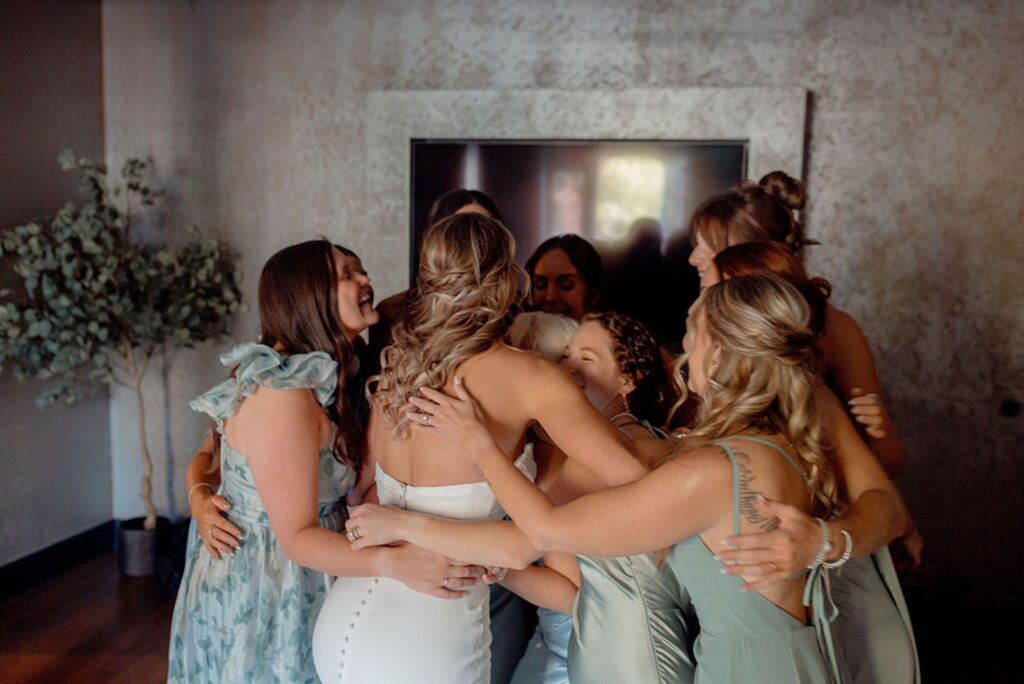 Bride hugging bridesmaids. 