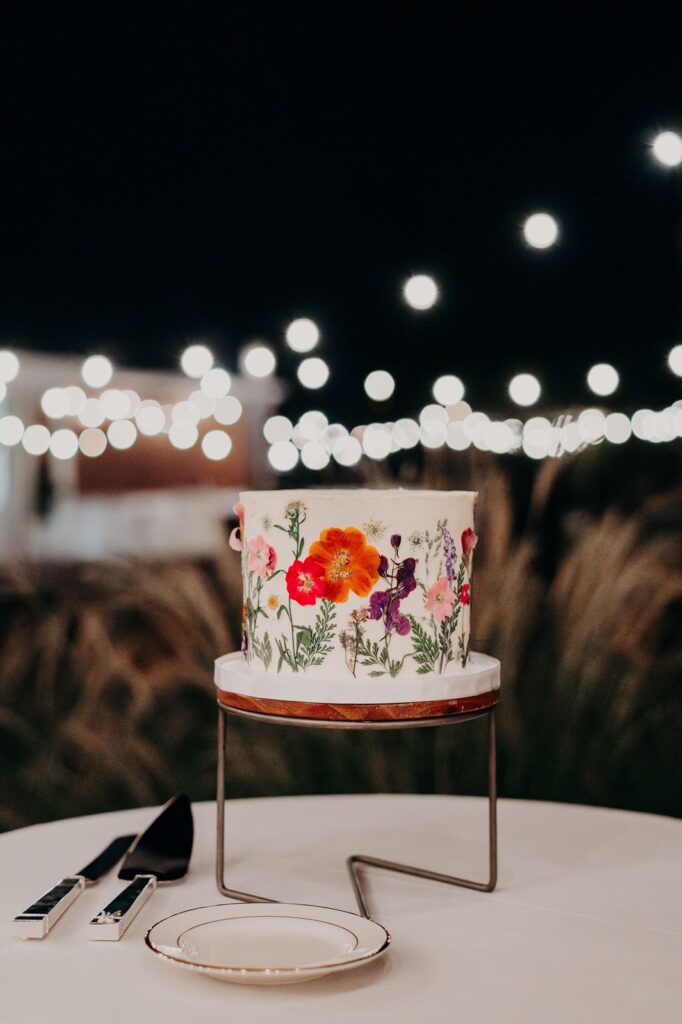 single-tier wedding cake with dried flowers pressed on the side.