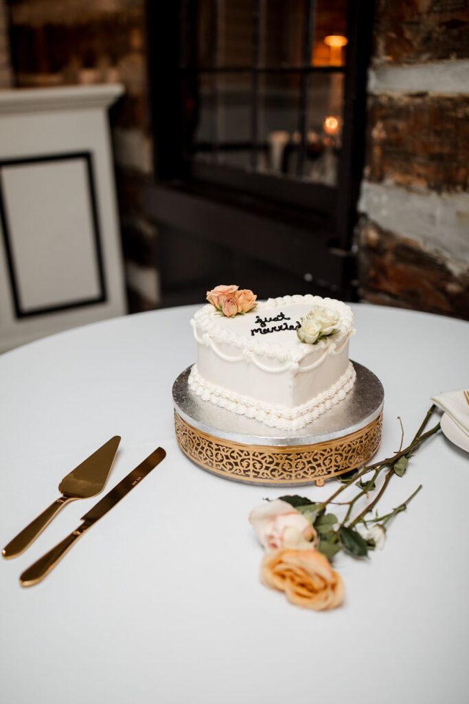 vintage heart-shaped, single-tier wedding cake with cake cutting set and flowers.