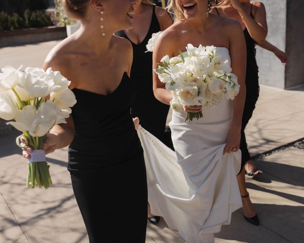 Bride and bridesmaid laughing while holding bouquets
