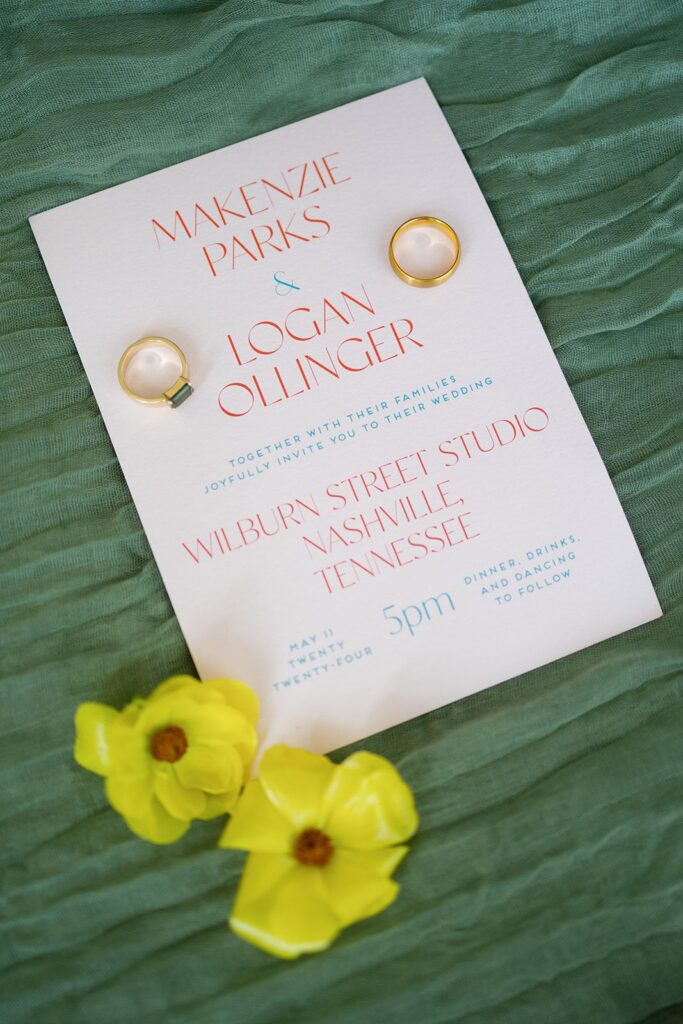 Wedding invitation with wedding rings and flowers on green fabric