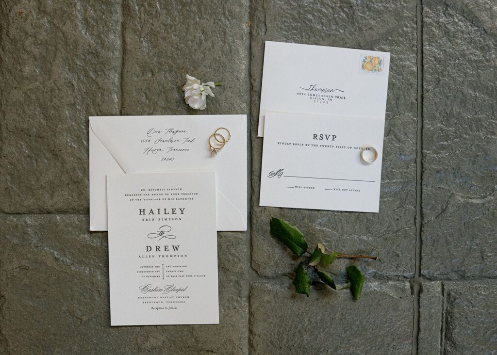 wedding stationery laid out with rings and flowers