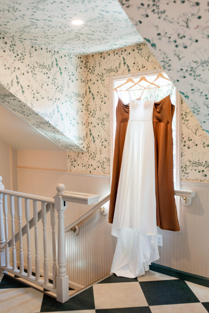 bridal gown and bridesmaid gowns hanging in front of a window